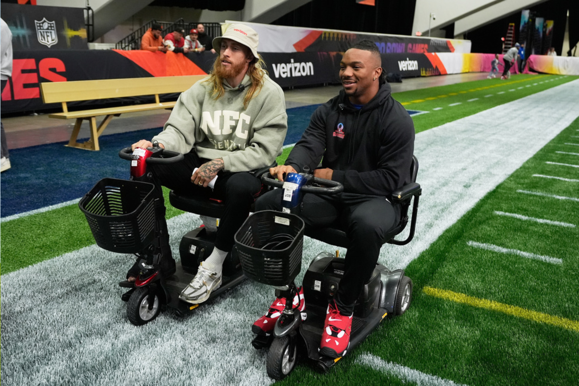 NFC tight end George Kittle, of the San Francisco 49ers, left, rides a scooter next to running back Bijan Robinson