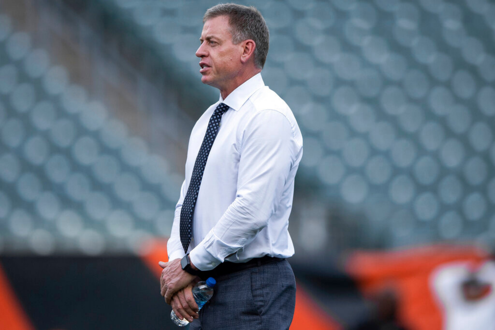 Troy Aikman stands on the field before an NFL football game