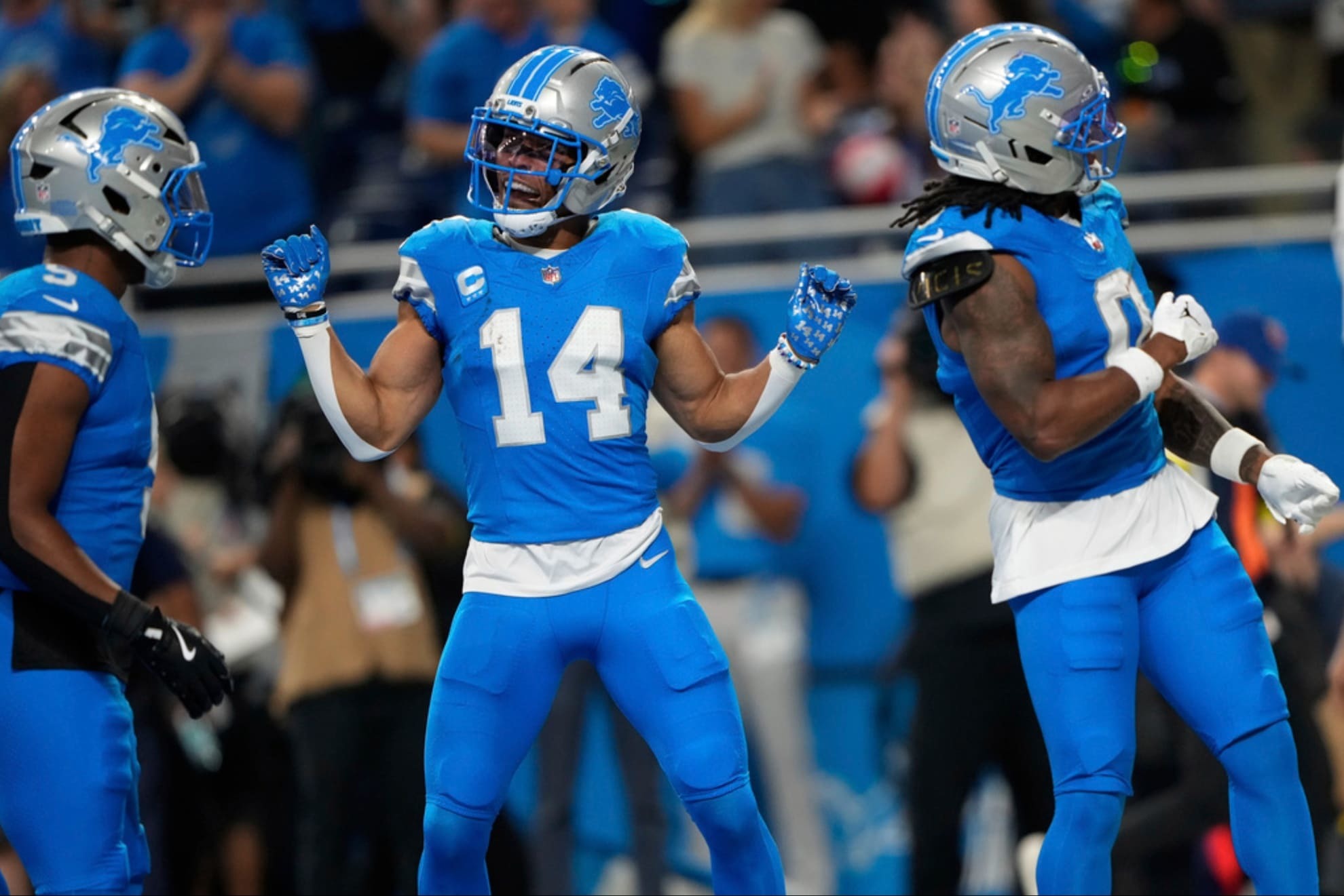 Detroit Lions running back Jahmyr Gibbs (0) celebrates with teammates Amon-Ra St. Brown (14) and David Montgomery (5).