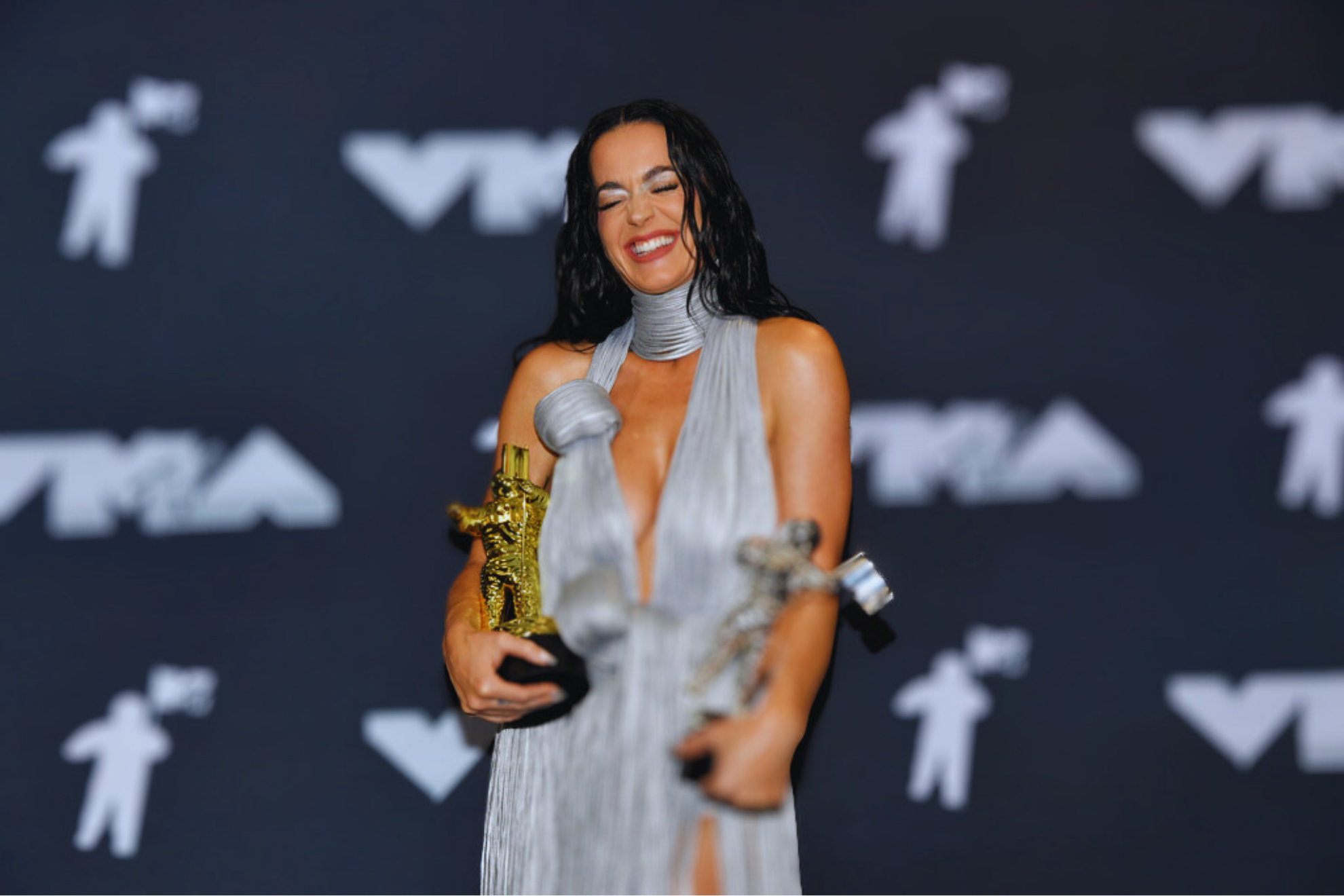 Katy Perry poses in the press room with the video vanguard award and VMAs most iconic performance award for "Roar" during the MTV Video Music Awards.