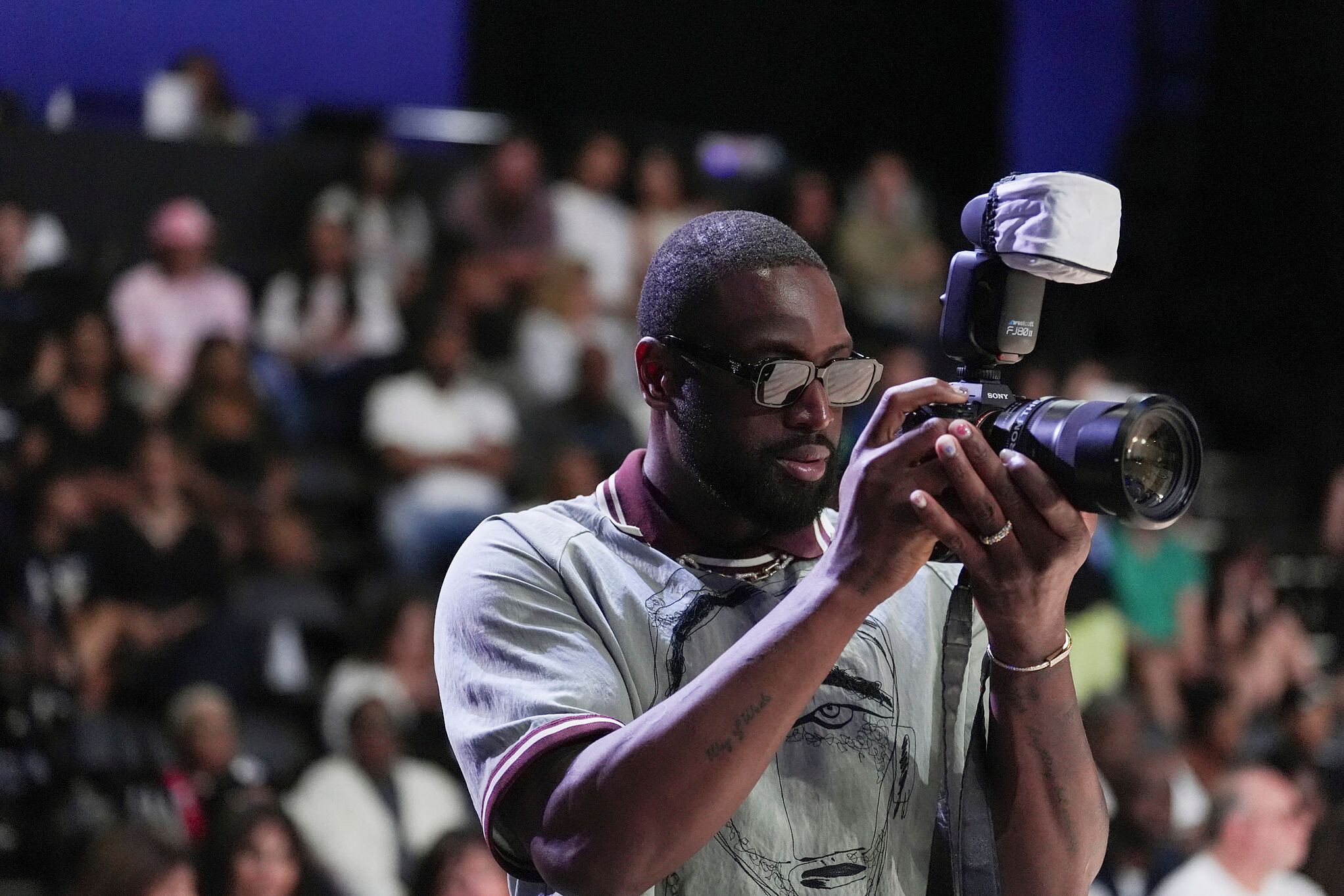 Former basketball player Dwayne Wade borrows a photographer's camera to take pictures during Unrivaled 3-on-3 basketball semifinal