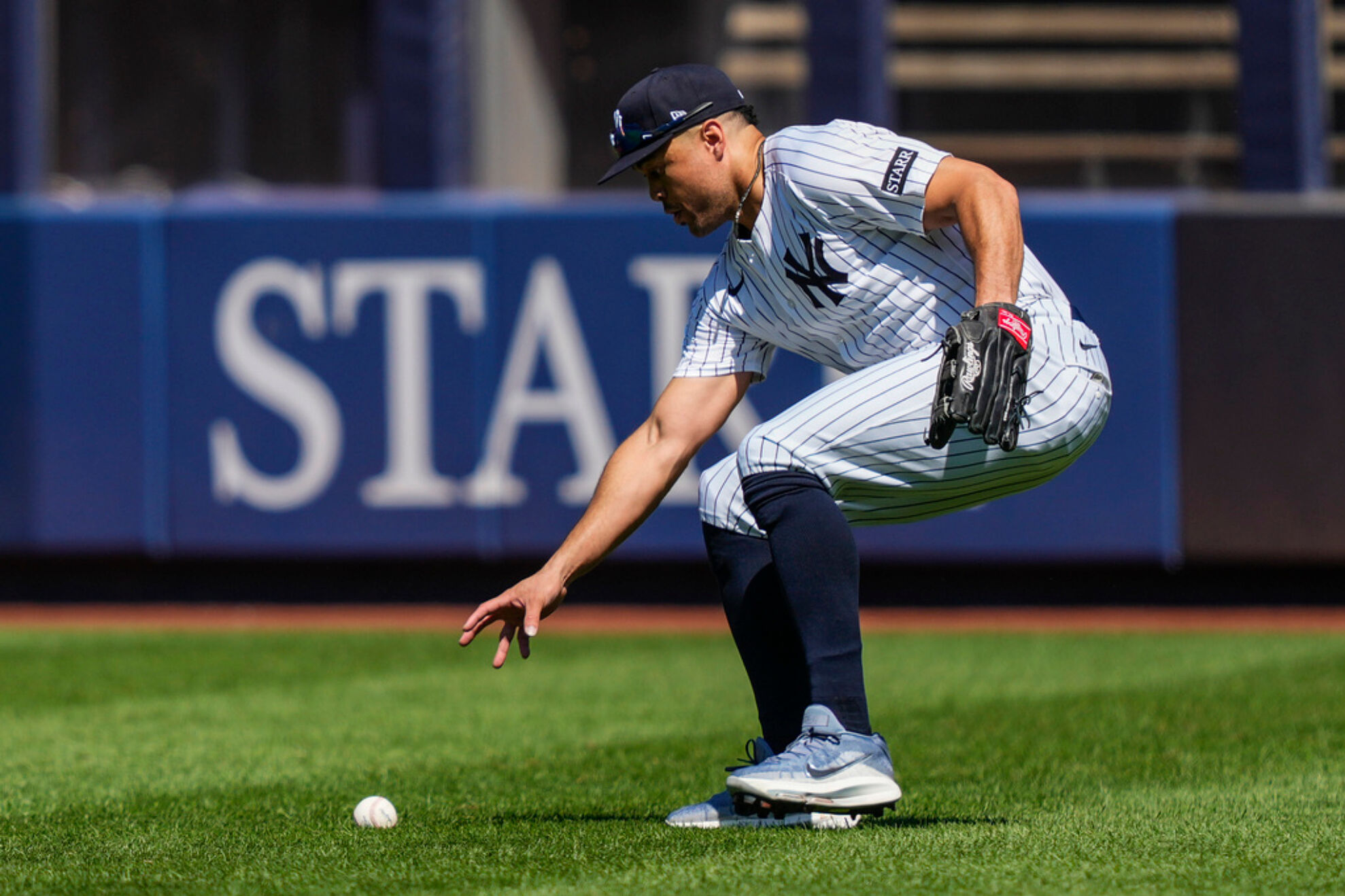 New York Yankees outfielder Giancarlo Stanton picks up a ball hit by Houston Astros' Jesús Sánchez (4) during the fourth inning of a baseball game against the Houston Astros, Saturday, Aug. 9, 2025, in New York.