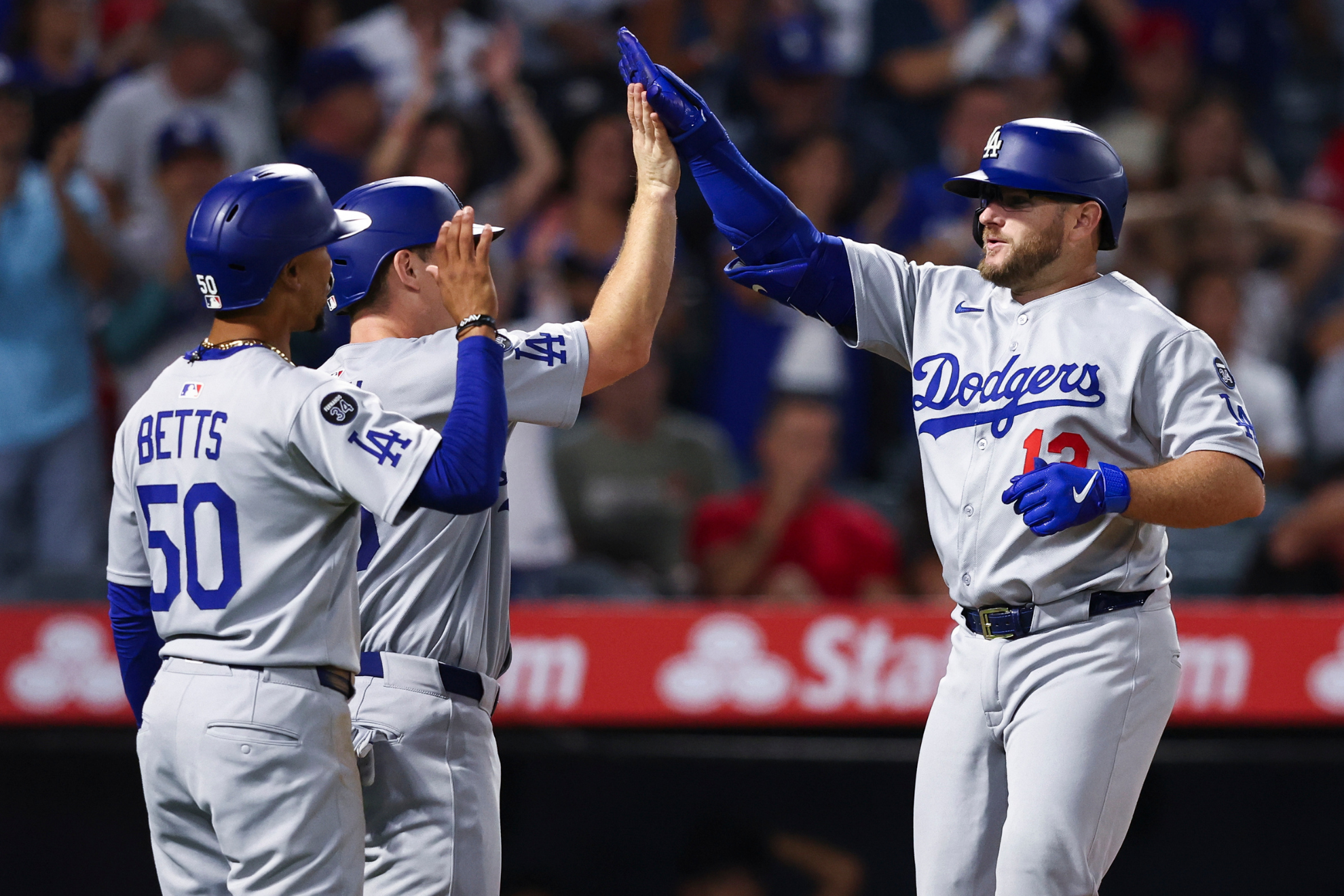 Los Angeles Dodgers' Max Muncy, right, celebrates with Will Smith, center, and Mookie Betts (50) after hitting a home run during the eighth inning of a baseball game against the Los Angeles Angels, Monday, Aug. 11, 2025, in Anaheim, Calif.
