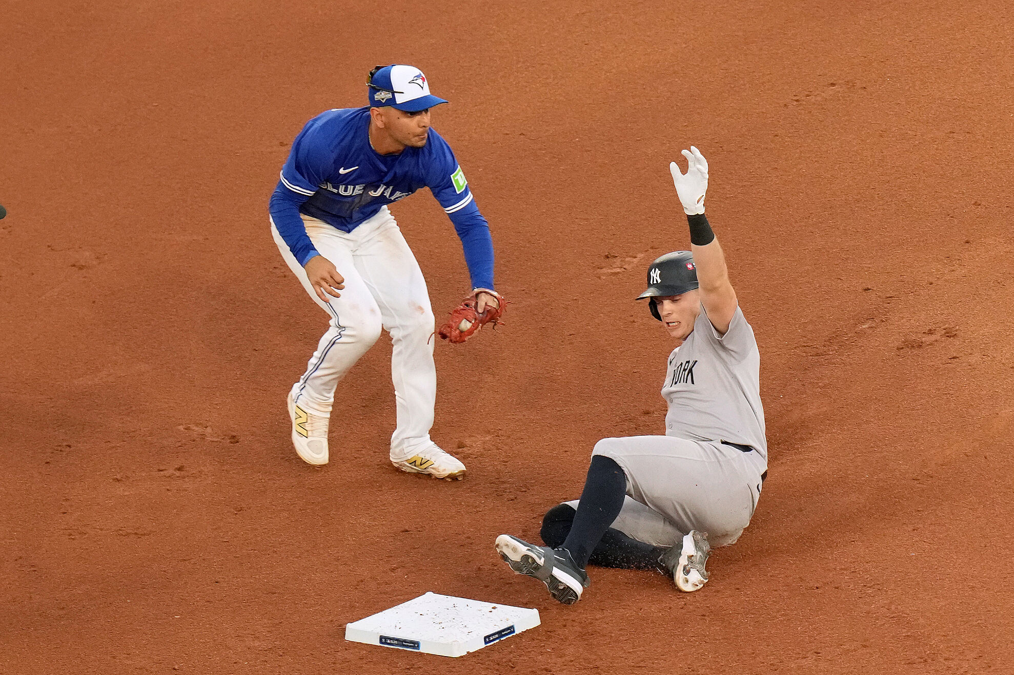 New York Yankees' Ben Rice, right, slides safely into second base after hitting a double as Toronto Blue Jays shortstop Andrés Giménez, left, misses the tag during the seventh inning of Game 2 of baseball's American League Division Series in Toronto, Sunday, Oct. 5, 2025.