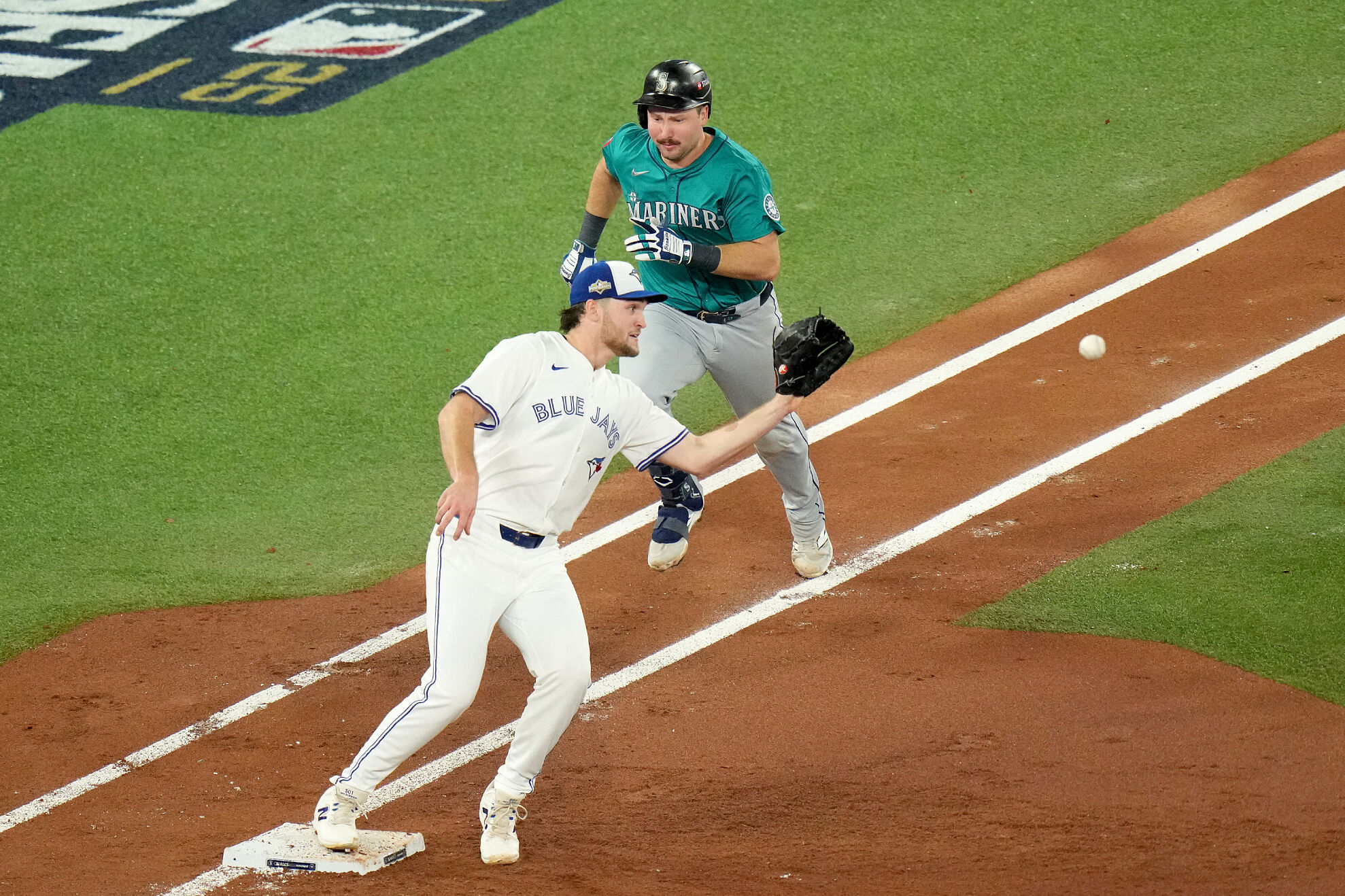 Toronto Blue Jays pitcher Trey Yesavage, bottom, makes a catch to put out Seattle Mariners' Cal Raleigh, top, to turn a double play during the third inning of Game 6 of baseball's American League Championship Series in Toronto, Sunday, Oct. 19, 2025.