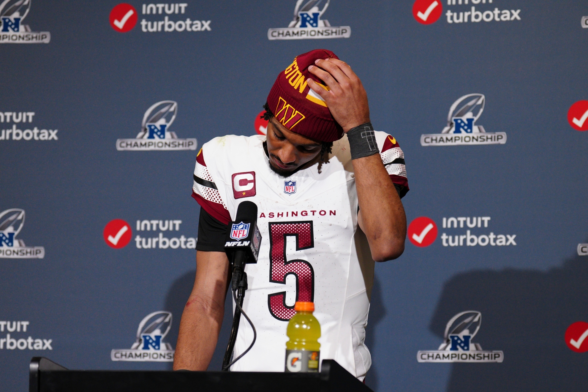 Jayden Daniels adjusts his cap during a news conference after the NFC Championship Game against the Philadelphia Eagles.
