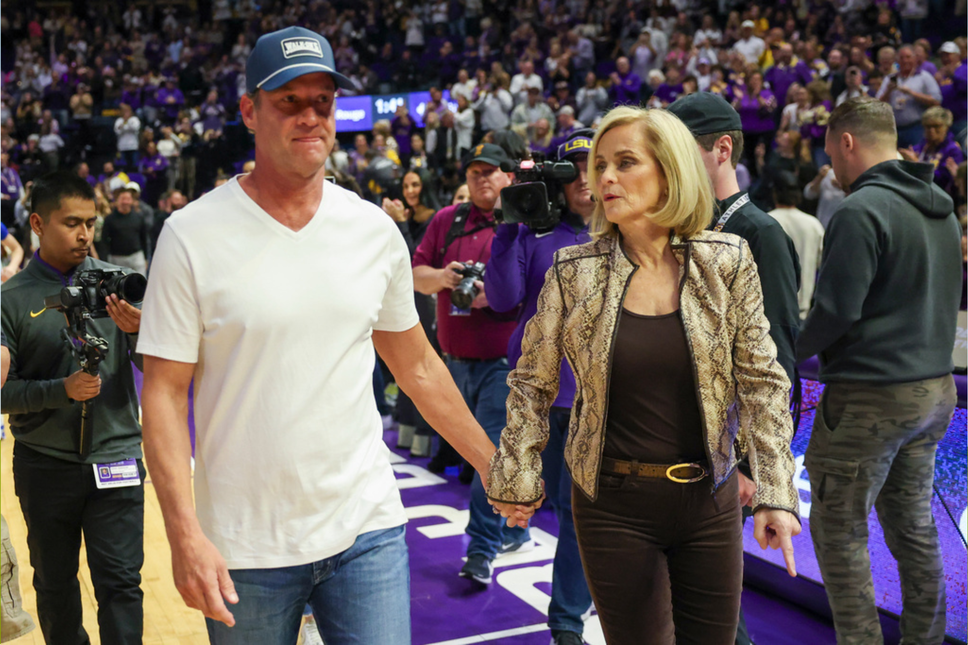 LSU head coach Kim Mulkey, right, brings head football coach Lane Kiffin out onto the court