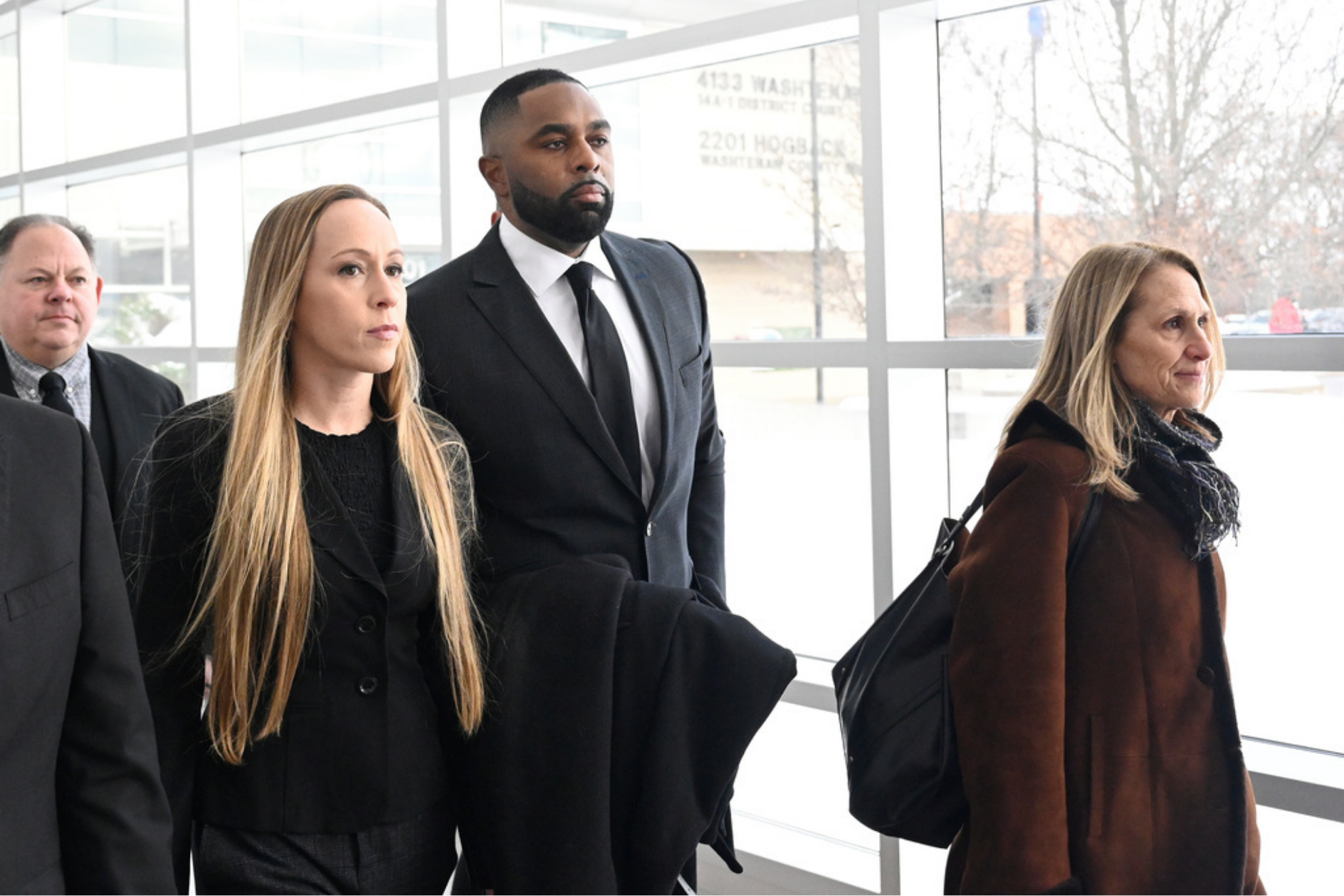 Former Michigan football coach Sherrone Moore, second from right, walks with his wife, Kelli Moore, left