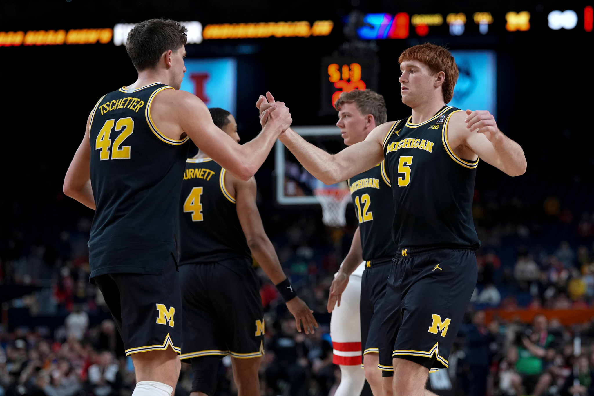 Michigan forward Oscar Goodman (5) greets forward Will Tschetter (42) after an NCAA college basketball tournament semifinal game against Arizona at the Final Four