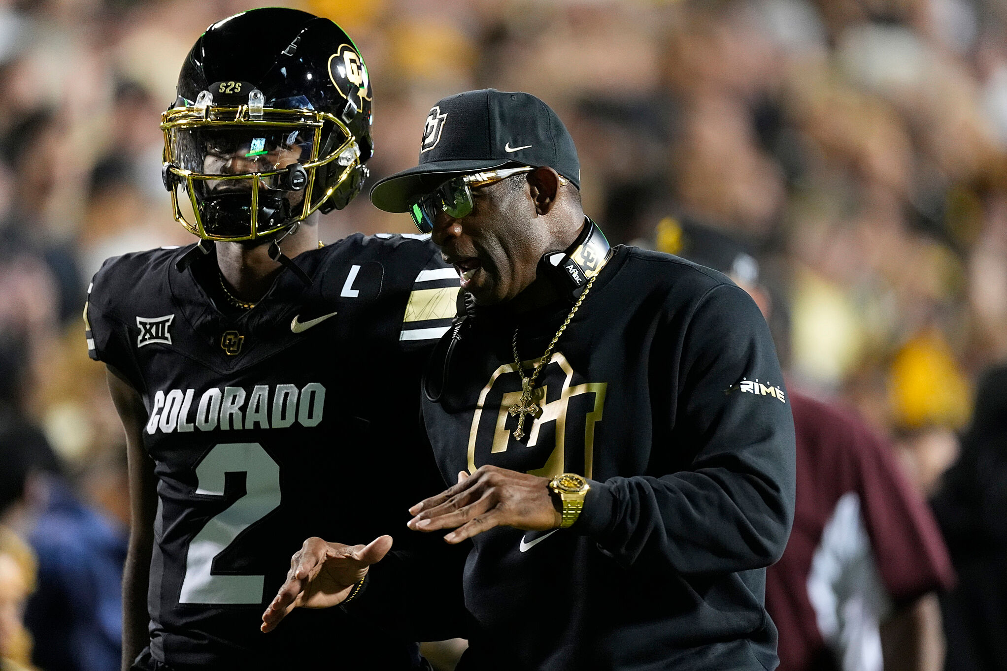 Colorado head coach Deion Sanders confers with his son, quarterback Shedeur Sanders (2)