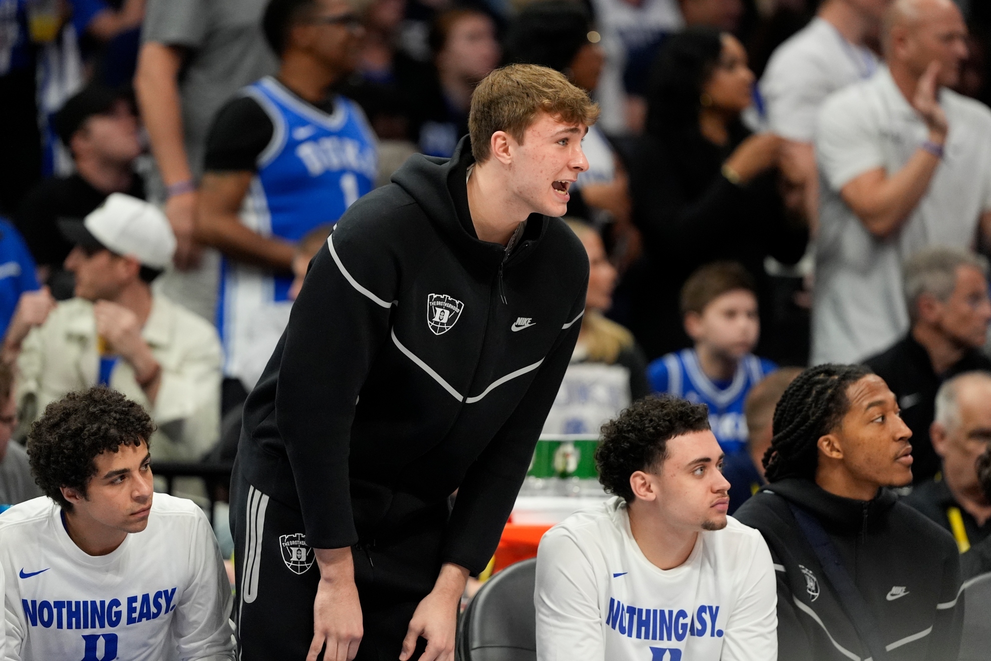 Cooper Flagg watches from the bench during the first half of an NCAA college basketball game.
