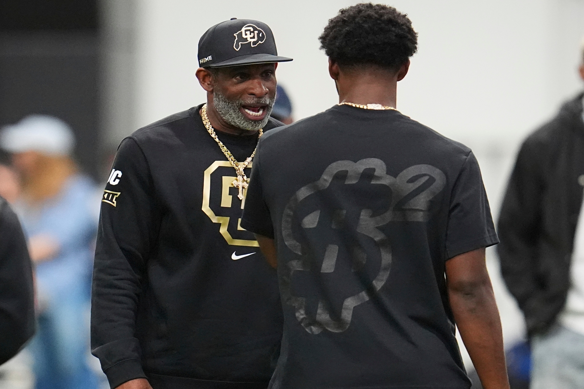 Deion Sanders talks with his son, quarterback Shedeur Sanders before passing drills at Colorado's NFL football pro day.