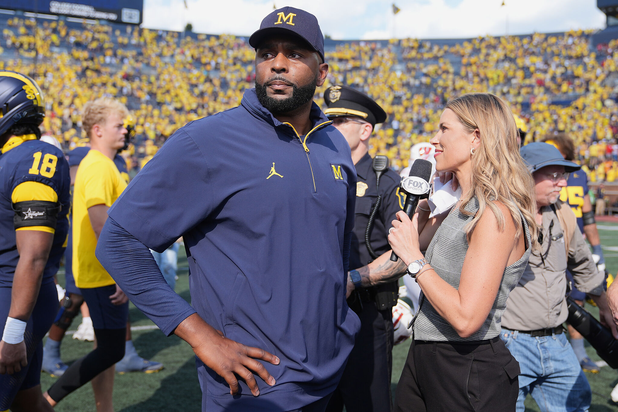 Michigan head coach Sherrone Moore gives a news interview after the team's win in an NCAA college football game against Wisconsin