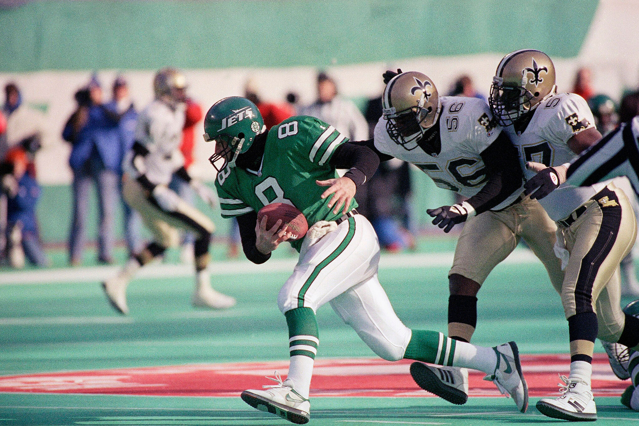 New York Jets quarterback Browning Nagle (8) runs away from New Orleans Saints Pat Swilling (56) and Rickey Jackson (57)