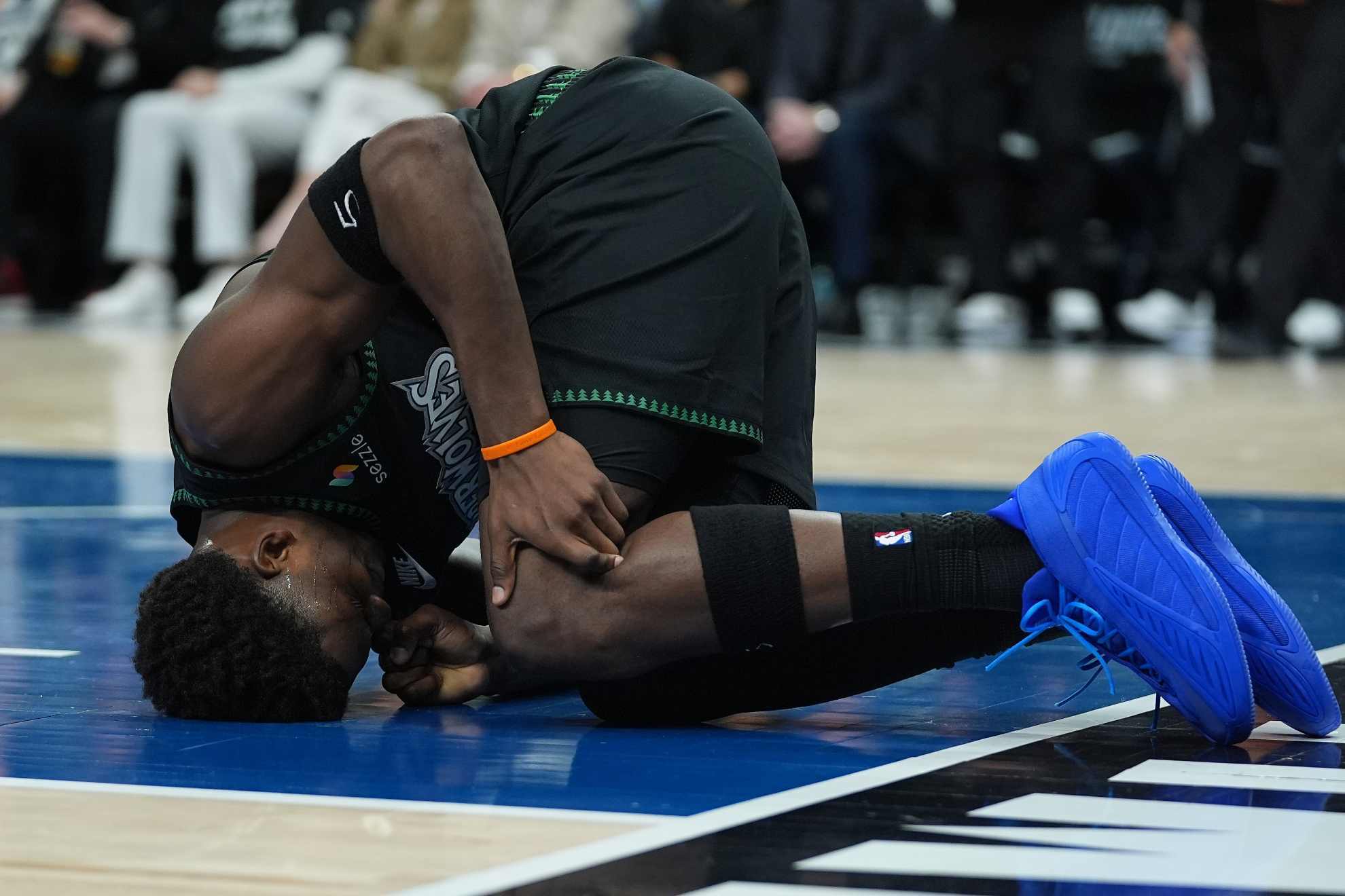 Anthony Edwards kneels on the court after sustaining an injury /
