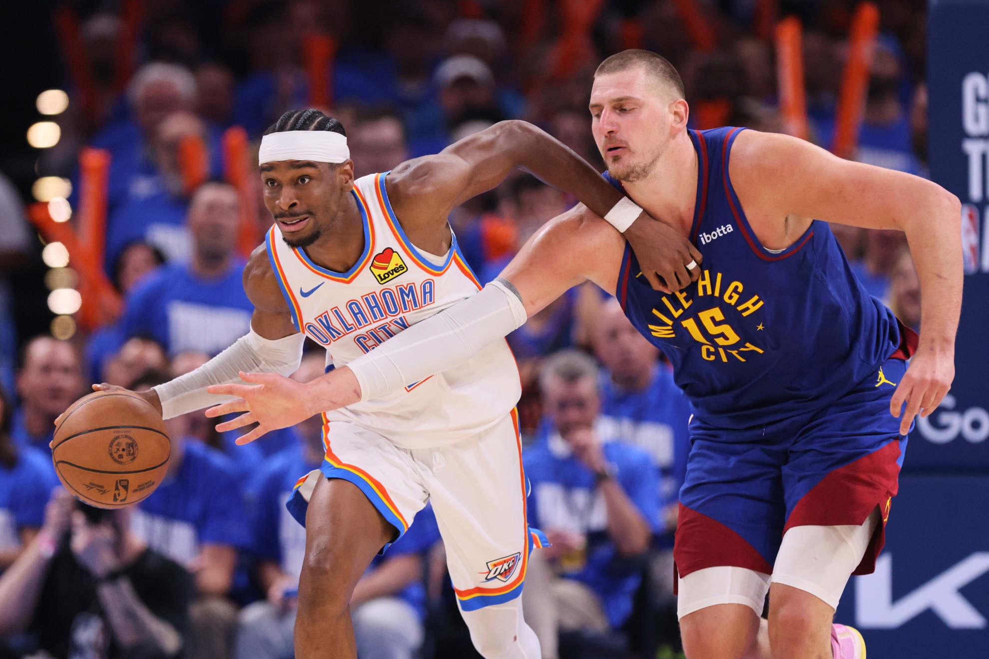 Oklahoma City Thunder's Shai Gilgeous-Alexander, left, advances the ball upcourt under pressure from Denver Nuggets center Nikola Jokic (15)