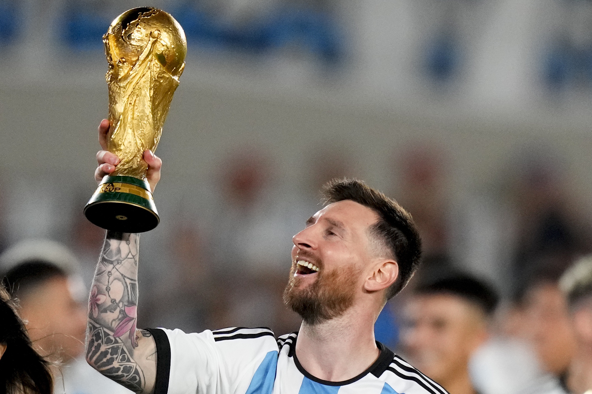 Lionel Messi hoists the winning team replica of the FIFA World Cup trophy.