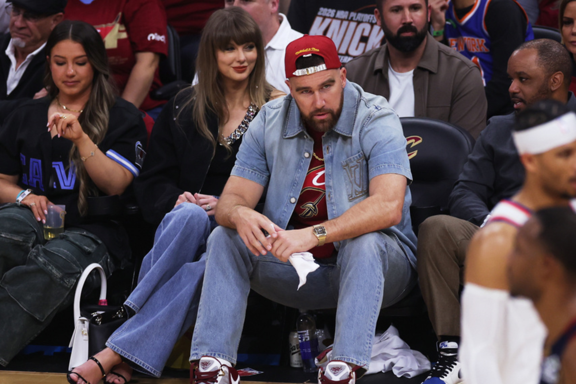 Taylor Swift y Travis Kelce sentados en la cancha durante el Juego 3 de las Finales de la Conferencia Este entre los Cleveland Cavaliers y los New York Knicks.