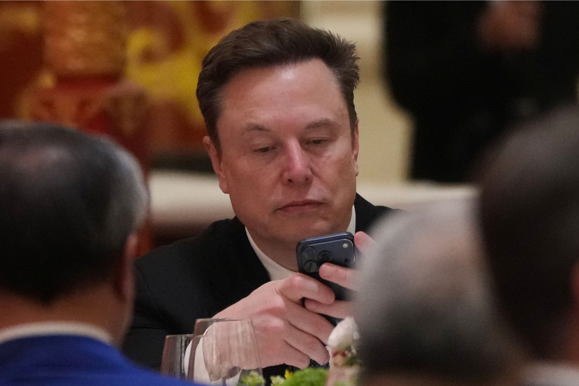 Elon Musk uses his phone during a state dinner for President Donald Trump and Chinese President Xi Jinping at the Great Hall of the People