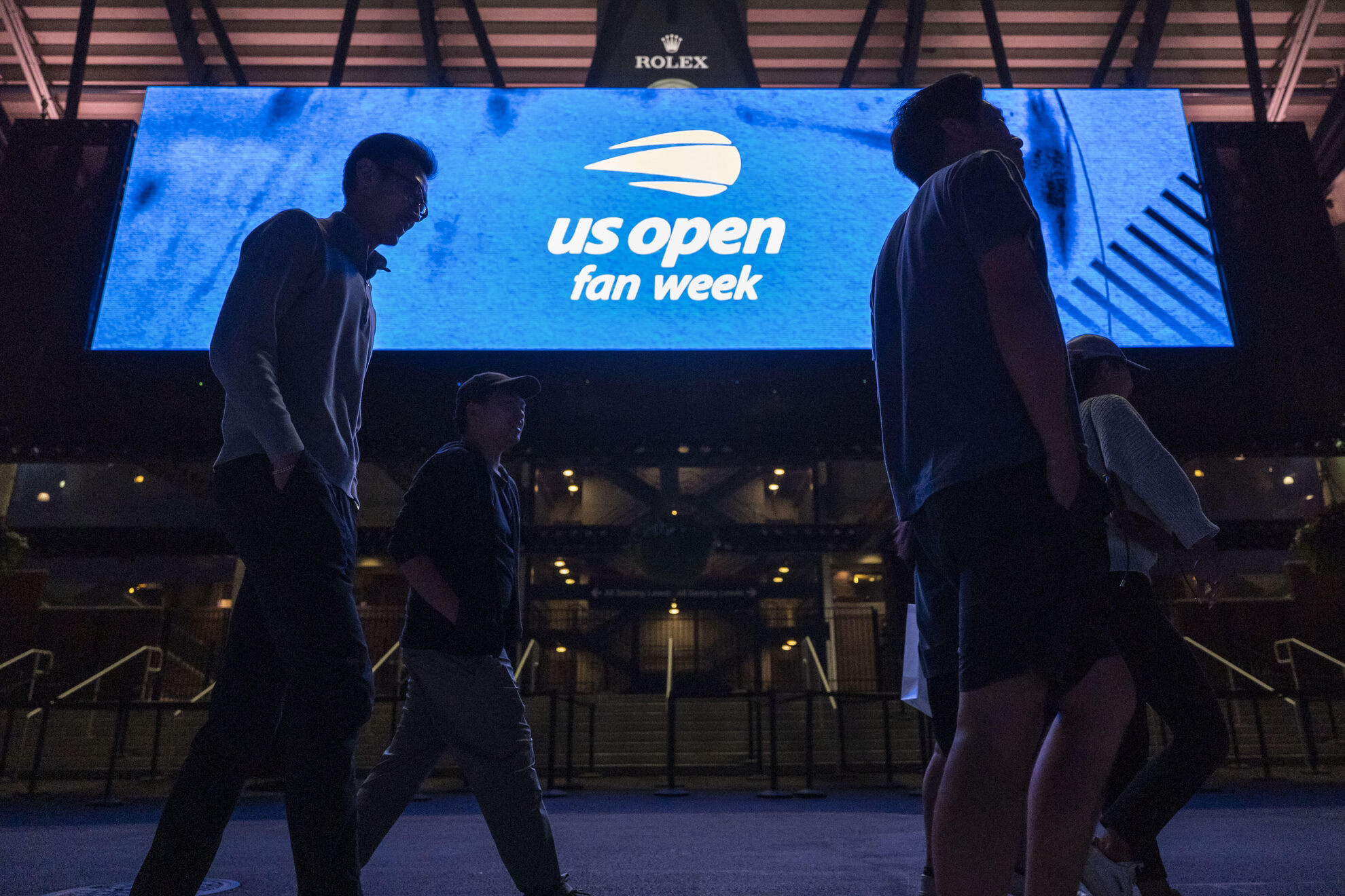 People walk past a screen showing a logo of U.S. Open fan week LAPRESSE