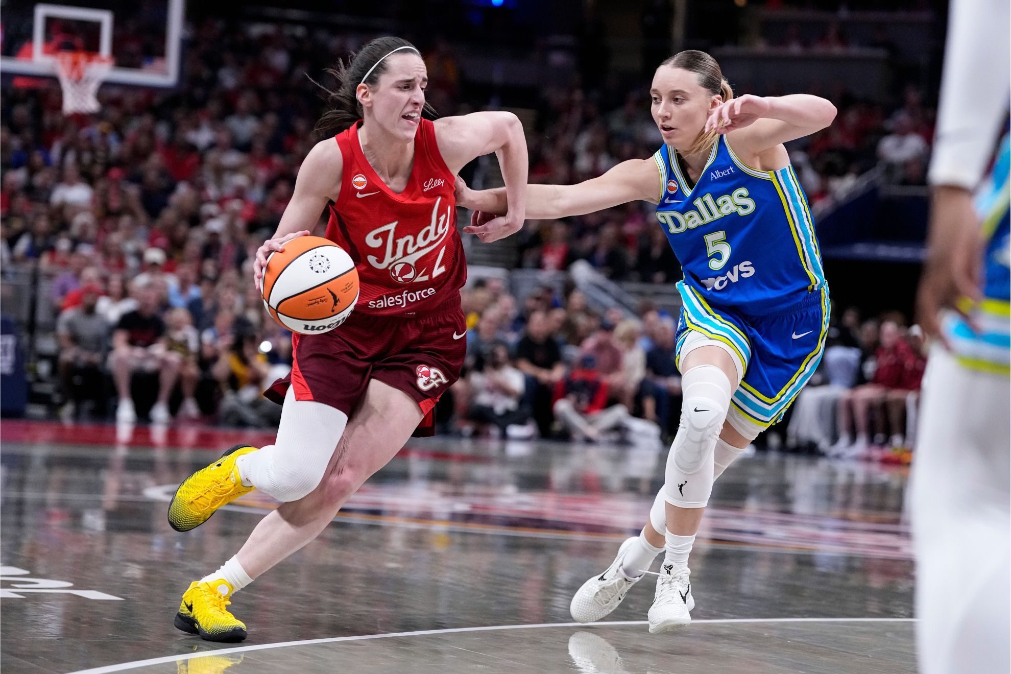 Indiana Fever guard Caitlin Clark, left, drives against Dallas Wings guard Paige Bueckers (5) in the first half of a WNBA basketball game in Indianapolis