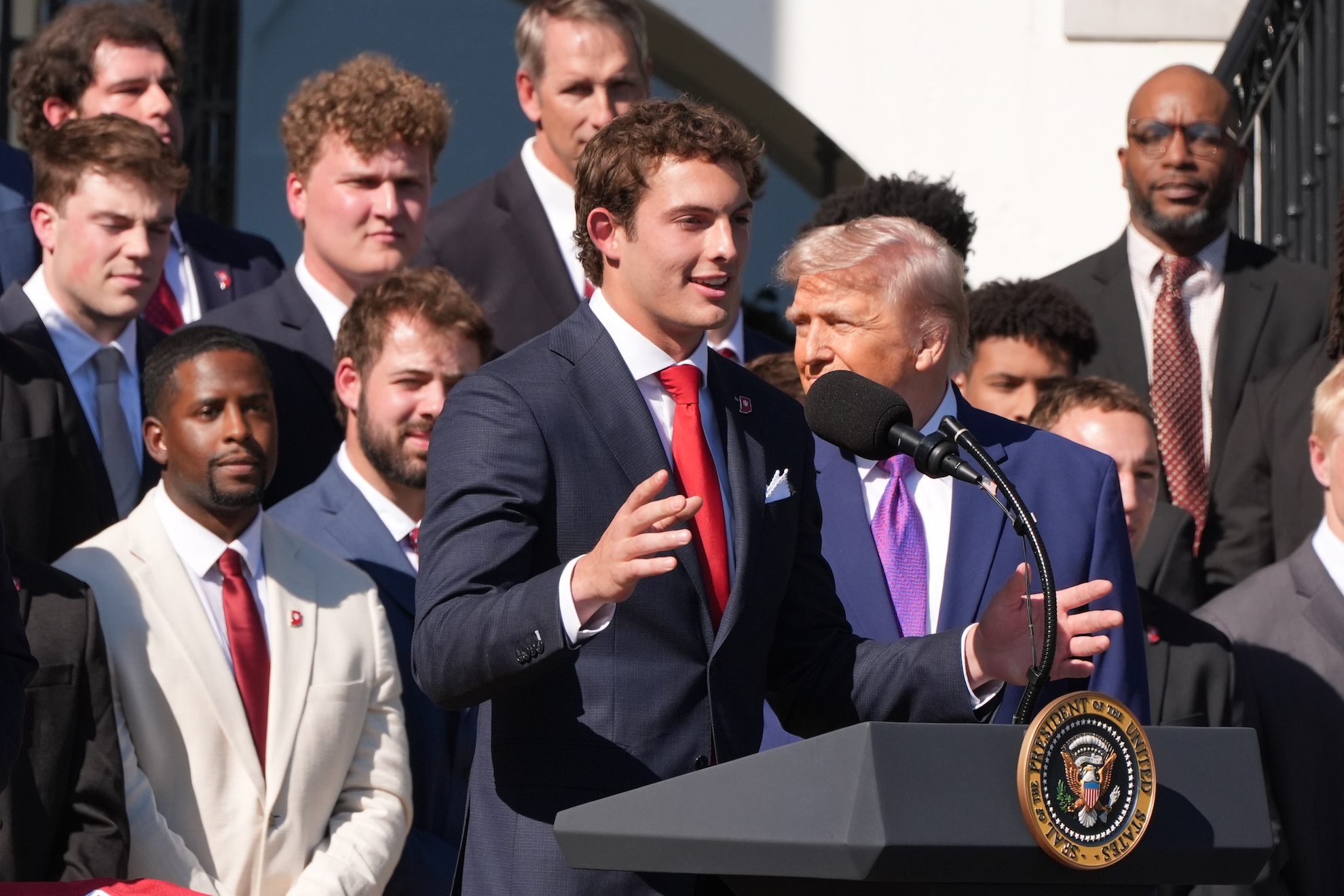 President Donald Trump listens as wide receiver Charlie Becker speaks LaPresse