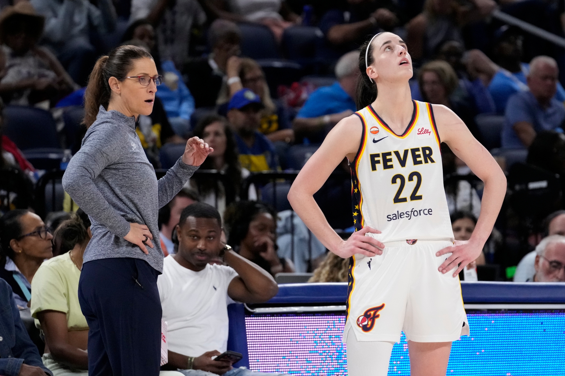 Indiana Fever guard Caitlin Clark, right, looks up the scoreboard as she listens to head coach Stephanie White