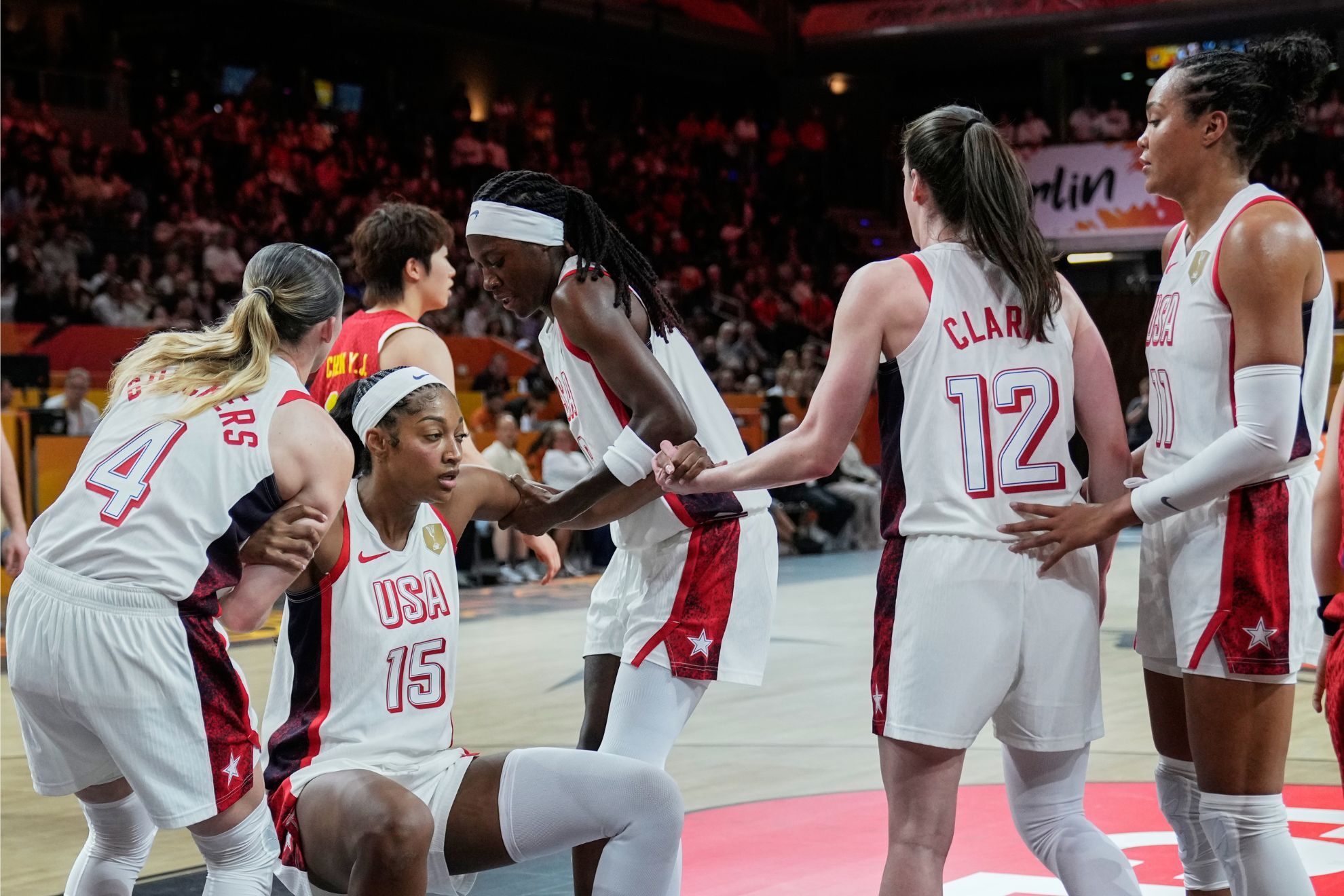 United States' Caitlin Clark, second right, helps Angel Reese to her feet during the Women's Basketball World Cup match between China and the United States in Berlin
