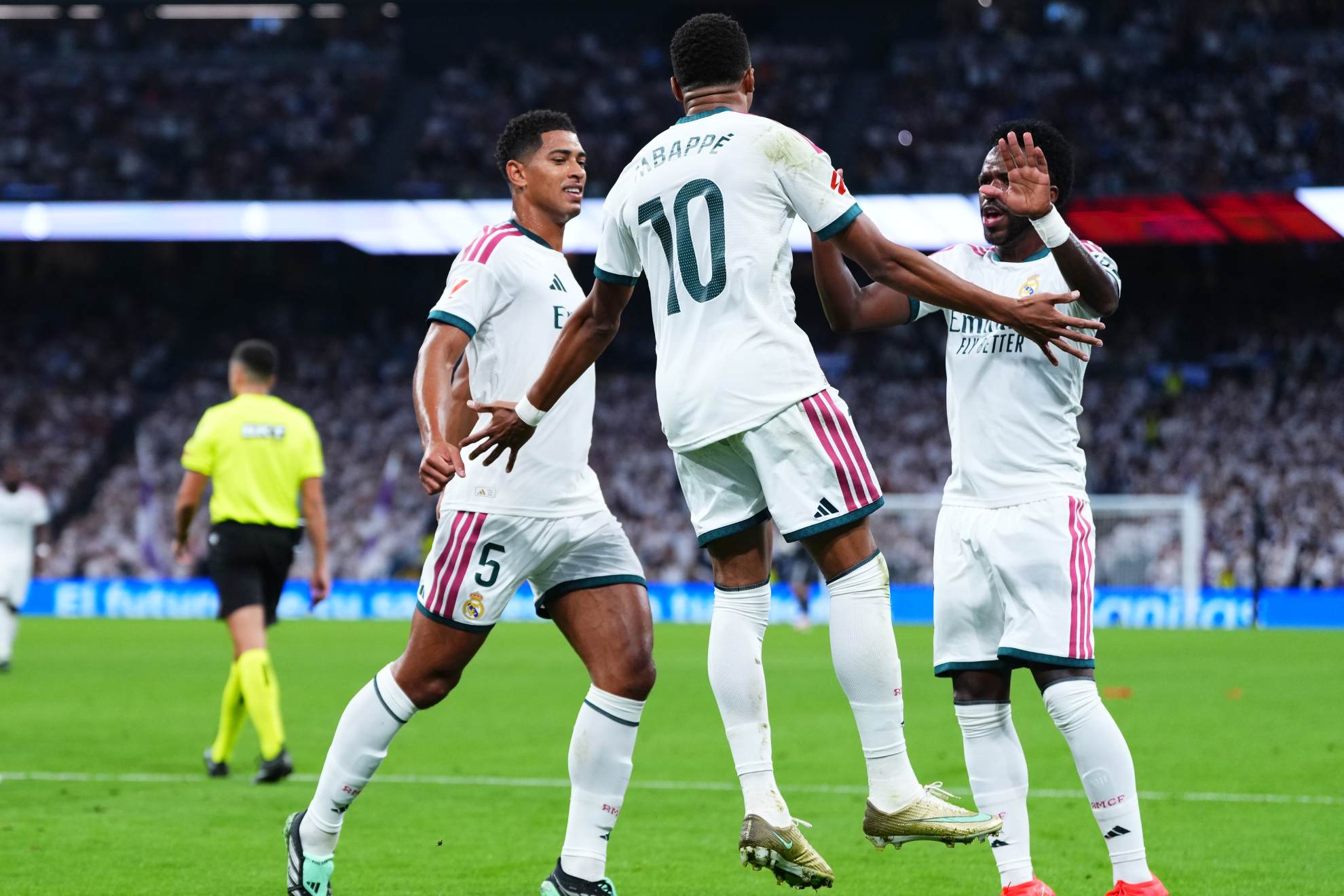 Kylian Mbappé celebrates scoring his team's first goal from the penalty spot alongside Jude Bellingham and Vinicius Junior during the Spanish La Liga match between Real Madrid and Rayo Vallecano Manu Fernandez