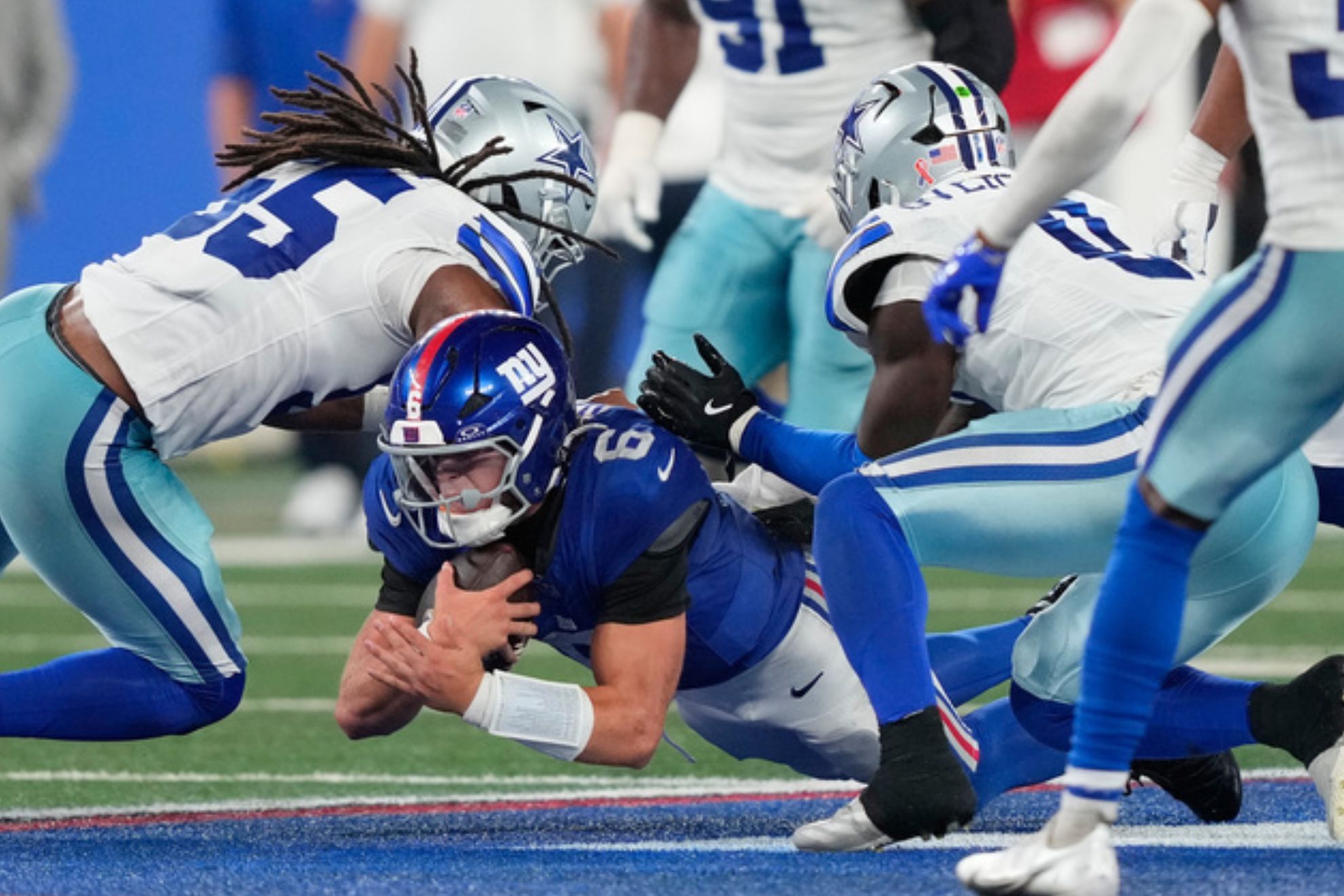 New York Giants quarterback Jaxson Dart (6) dives for yardage against Dallas Cowboys linebacker Jaishawn Barham, left, and linebacker DeMarvion Overshown
