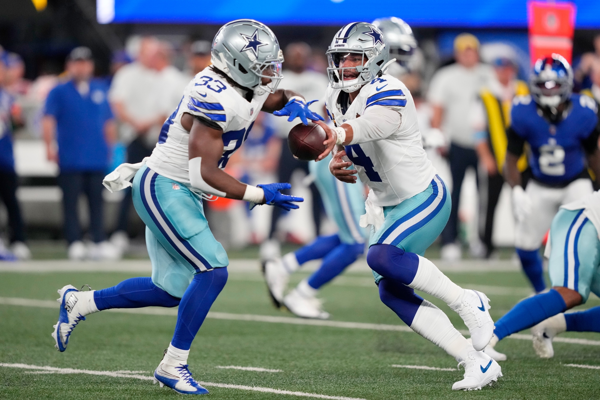 Dallas Cowboys quarterback Dak Prescott, right, hands off to running back Javonte Williams against the New York Giants