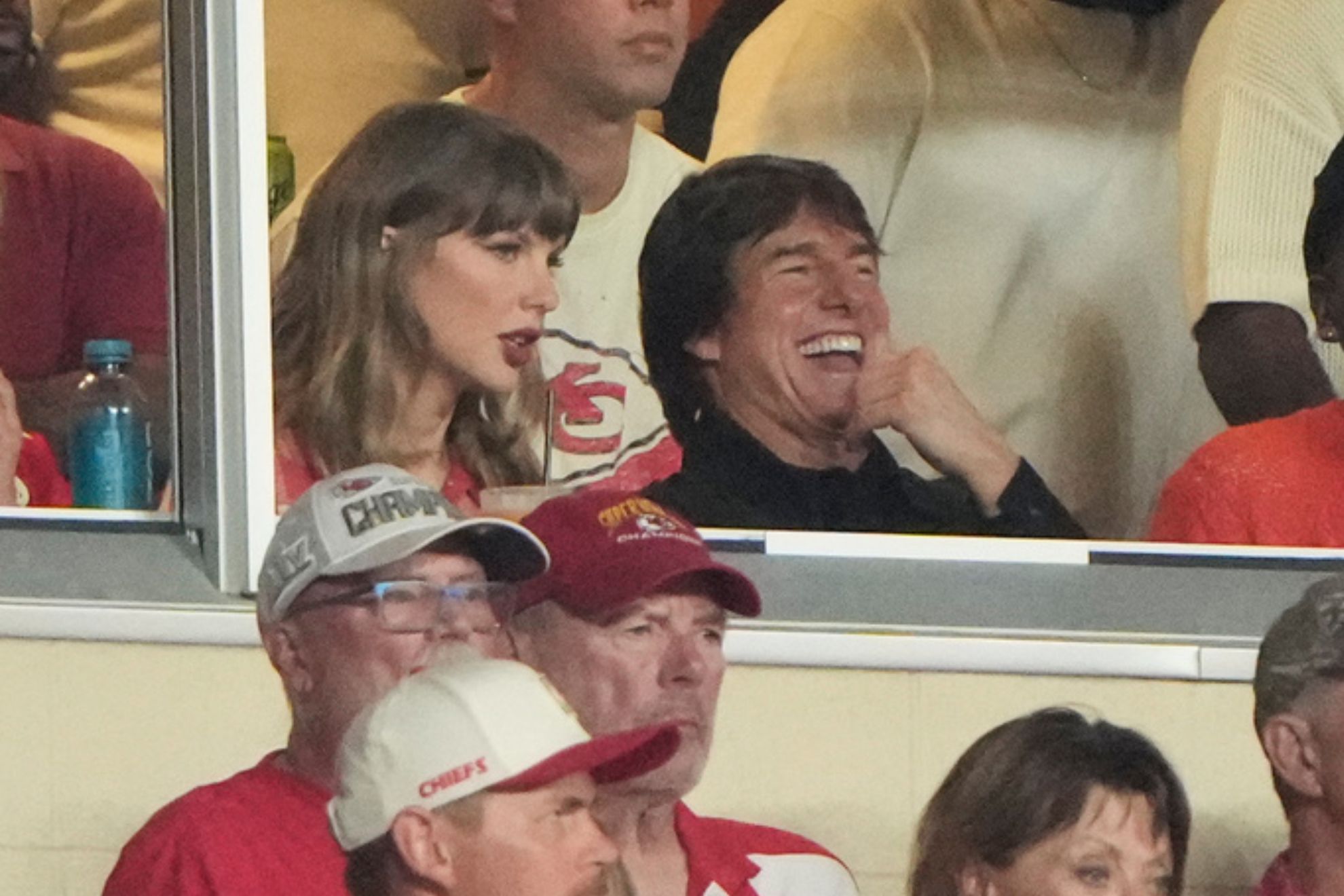 Taylor Swift, left, sits with Tom Cruise, center, while watching the first half of an NFL football game between the Kansas City Chiefs and the Denver Broncos