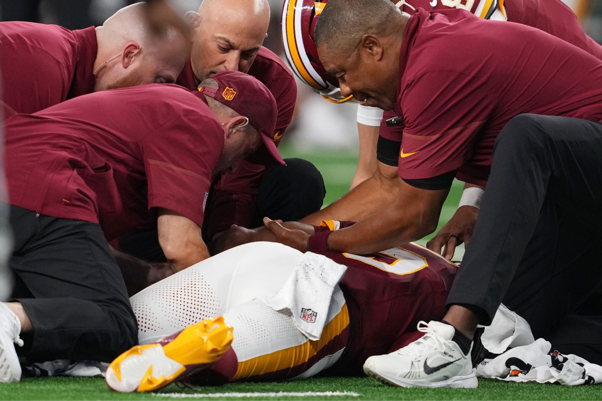 Trainers attend to Washington Commanders quarterback Jayden Daniels (5)
