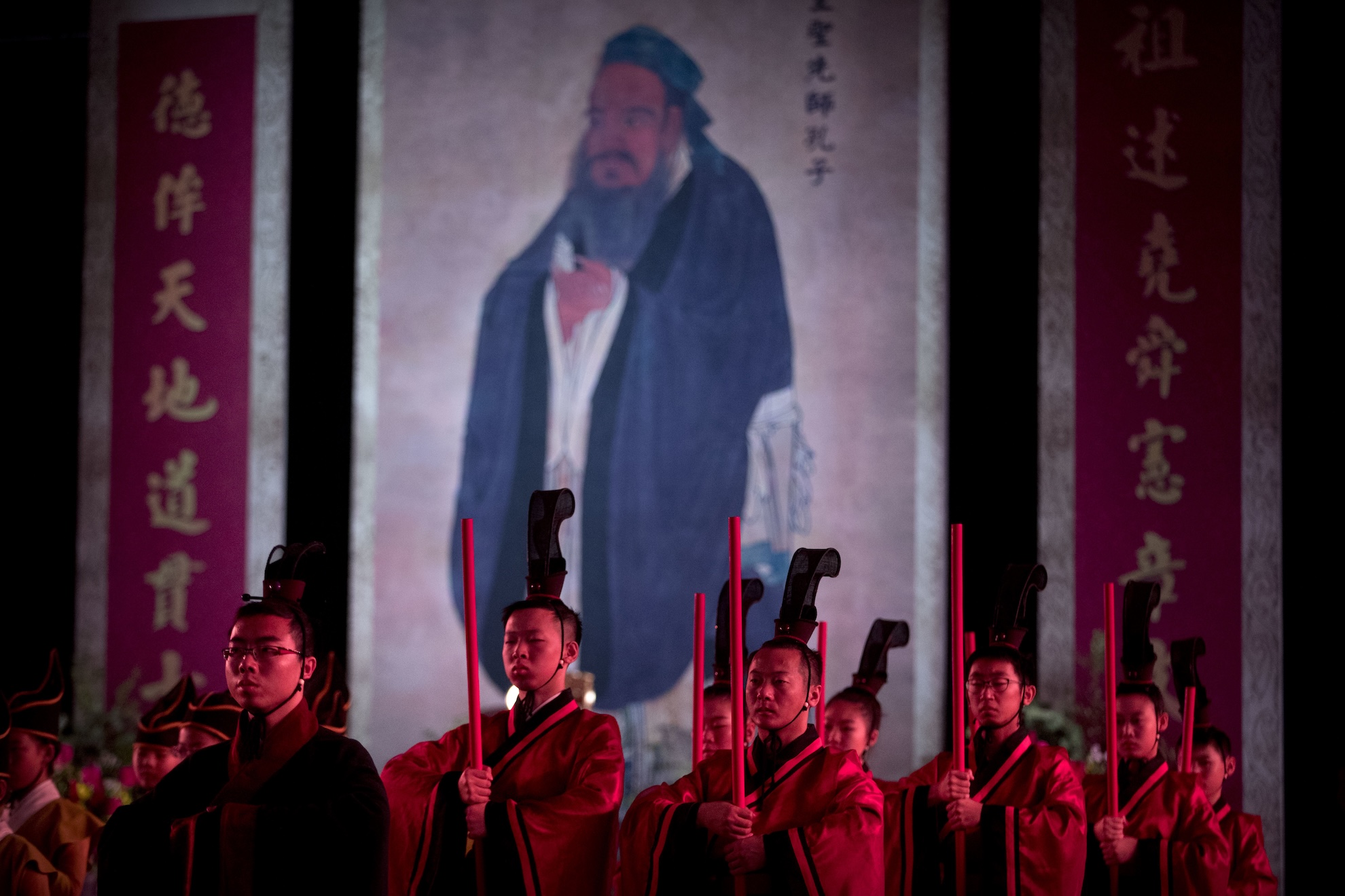 Participants in traditional dress stand near a portrait of Confucius in 2016 during a ceremony to observe the 2567th anniversary of his birth in Beijing. LaPresse