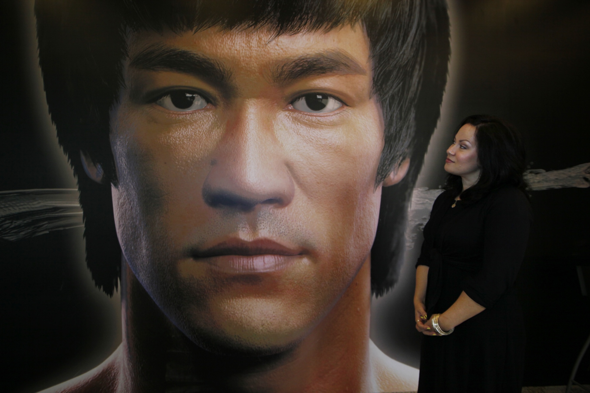 Shannon Lee, daughter of the late Kung Fu star Bruce Lee, poses in front of a promotional poster for Lee's memorial exhibition at the Hong Kong Heritage Museum LAPRESSE