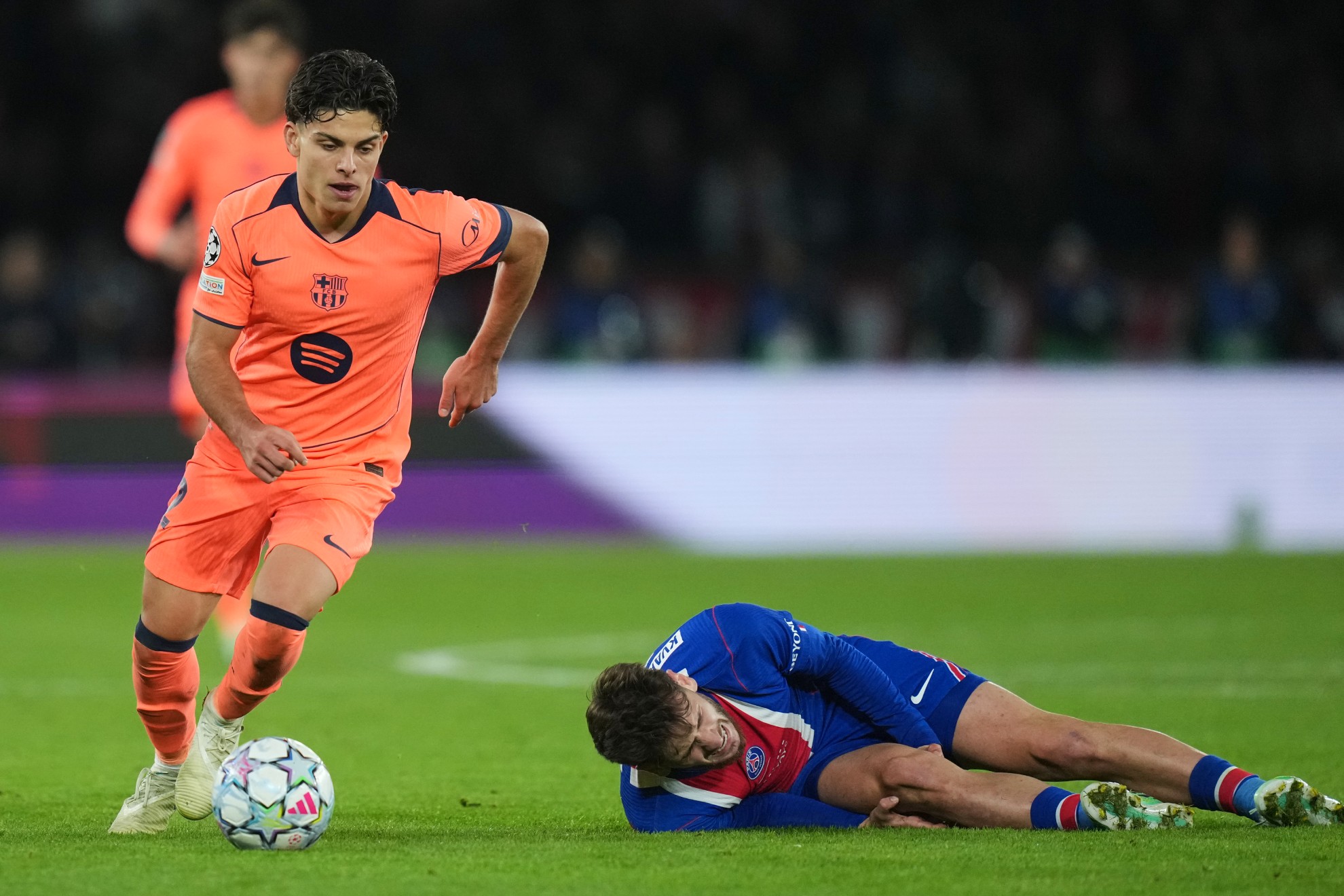 PSG's Khvicha Kvaratskhelia grimaces in pain after a challenges for the ball with Xavi Espart /