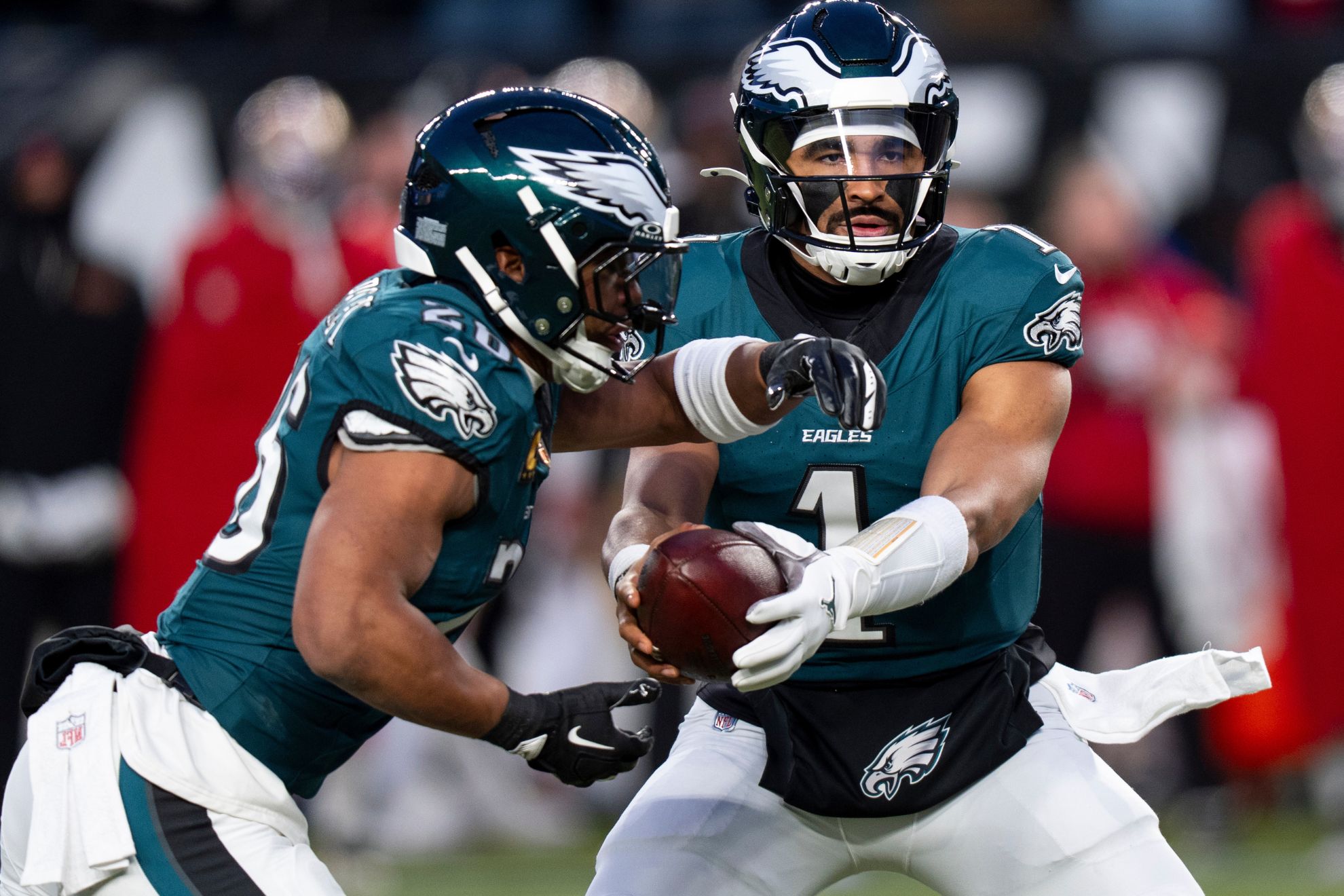 Philadelphia Eagles quarterback Jalen Hurts, right, hands the ball off to running back Saquon Barkley